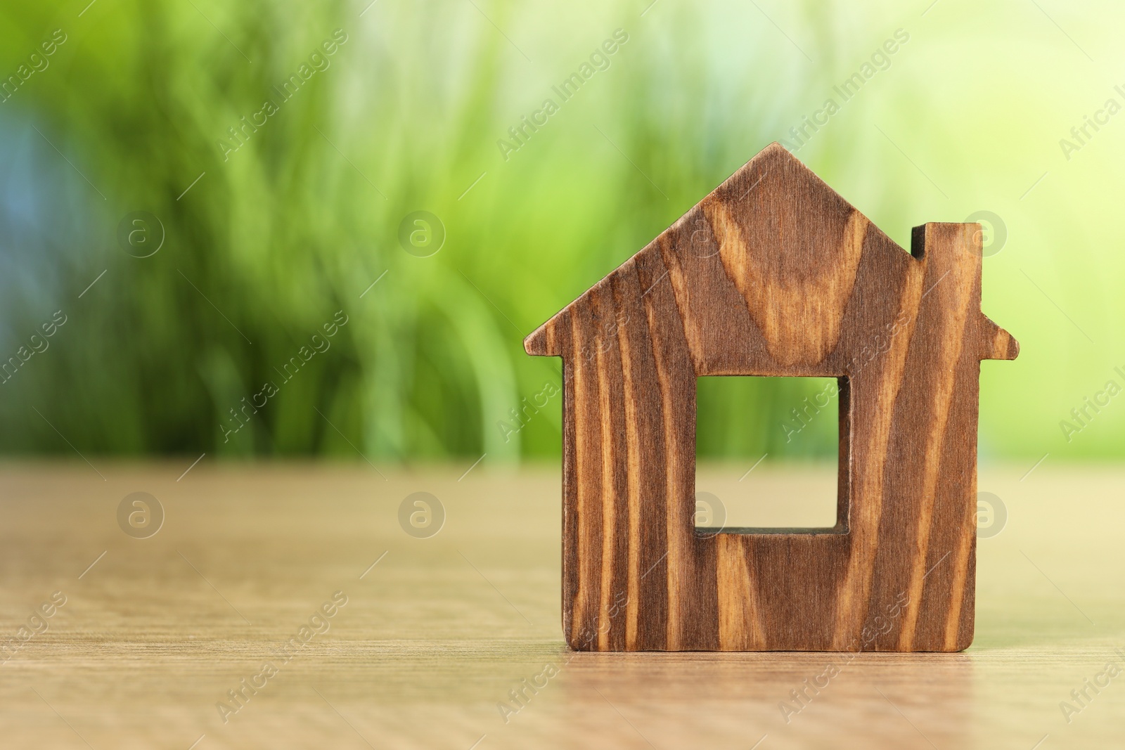 Photo of Mortgage concept. House model on wooden table against blurred green background, space for text