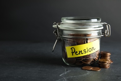 Photo of Glass jar with label PENSION and coins on dark table. Space for text