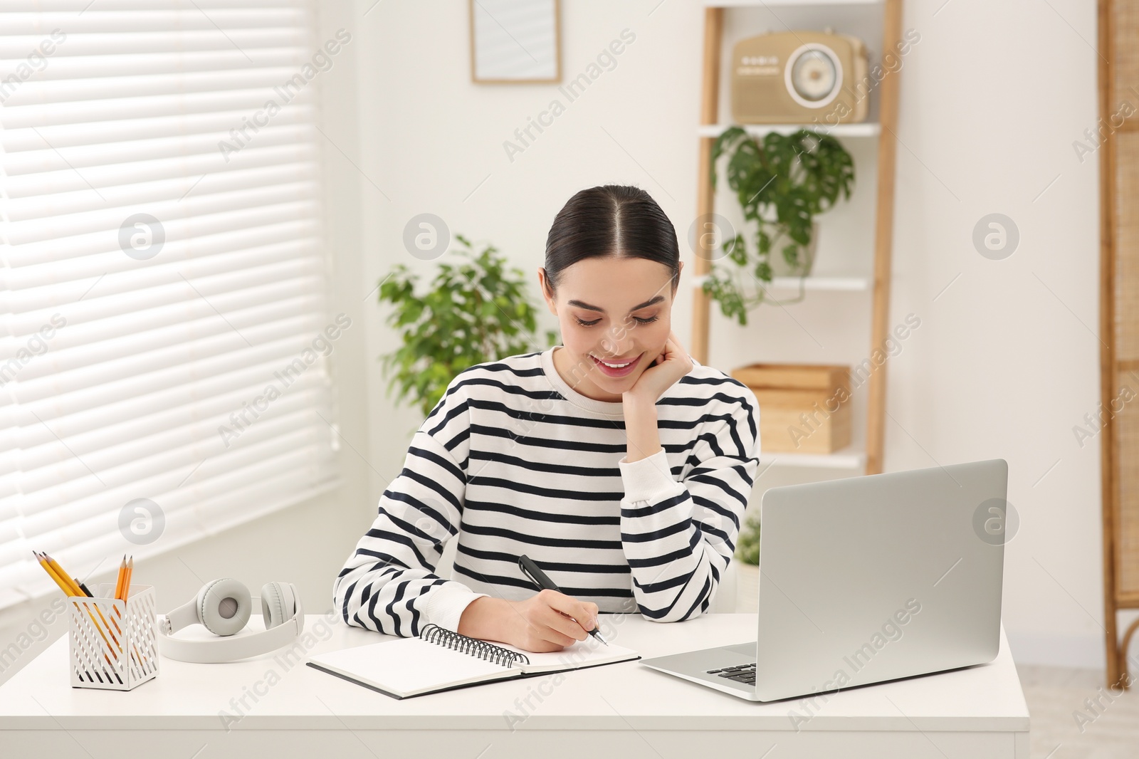 Photo of Online translation course. Student writing near laptop at home