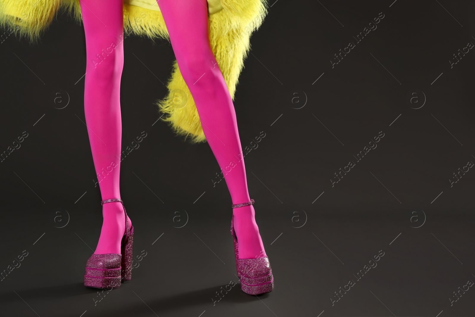 Photo of Woman wearing pink tights and high heeled shoes with platform and square toes on dark grey background, closeup. Space for text