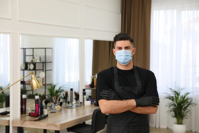 Professional stylist with protective mask in salon, space for text. Hairdressing services during Coronavirus quarantine