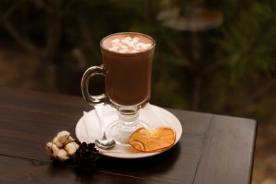 Photo of Cup of aromatic cacao on table against blurred background