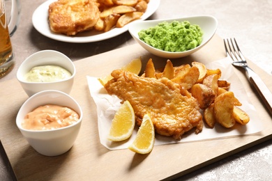 Photo of British traditional fish, potato chips and mushy peas on color background