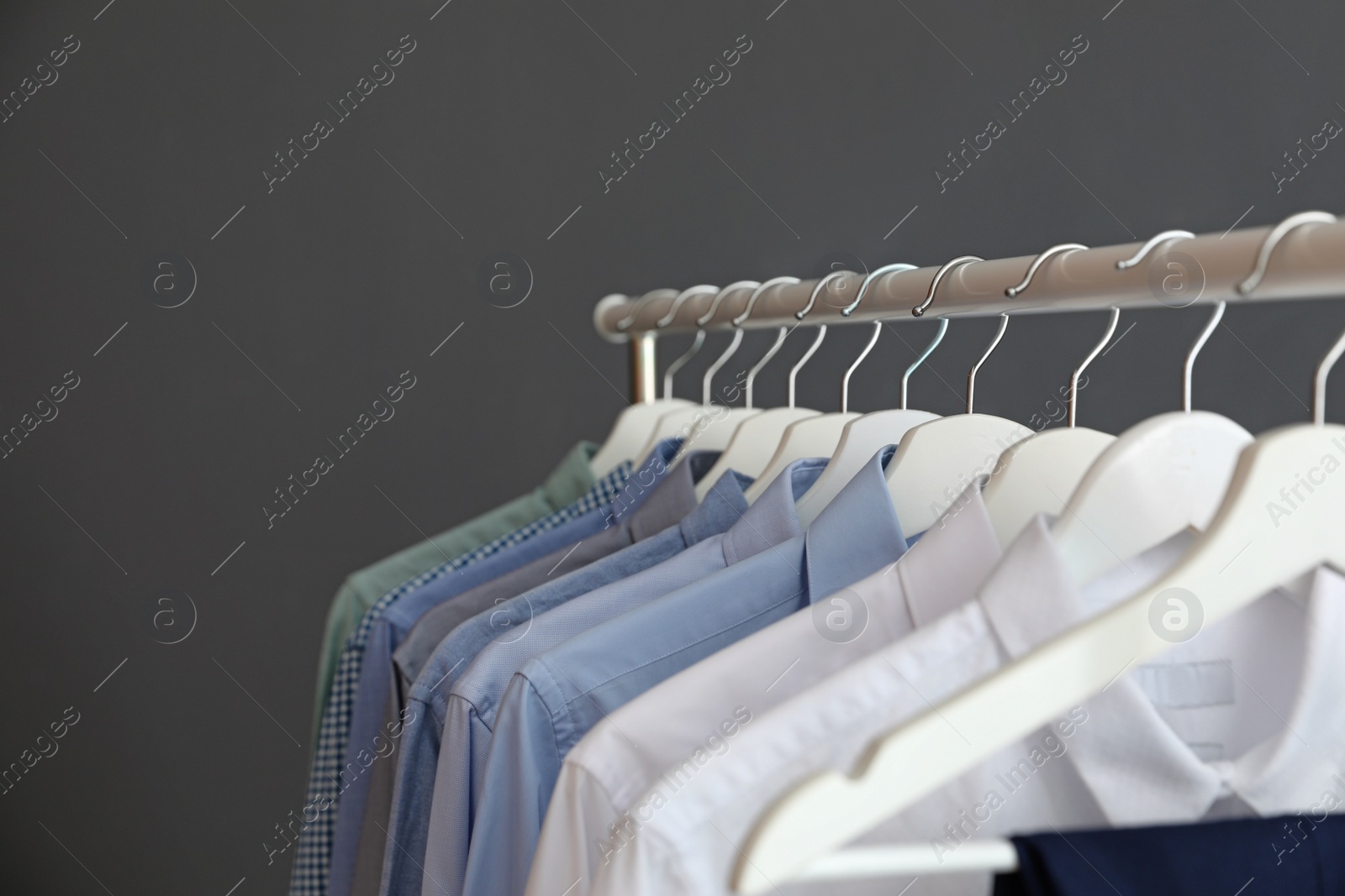 Photo of Wardrobe rack with men's clothes against grey background. Space for text