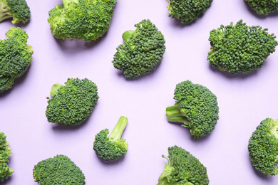 Photo of Fresh tasty broccoli on violet background, flat lay