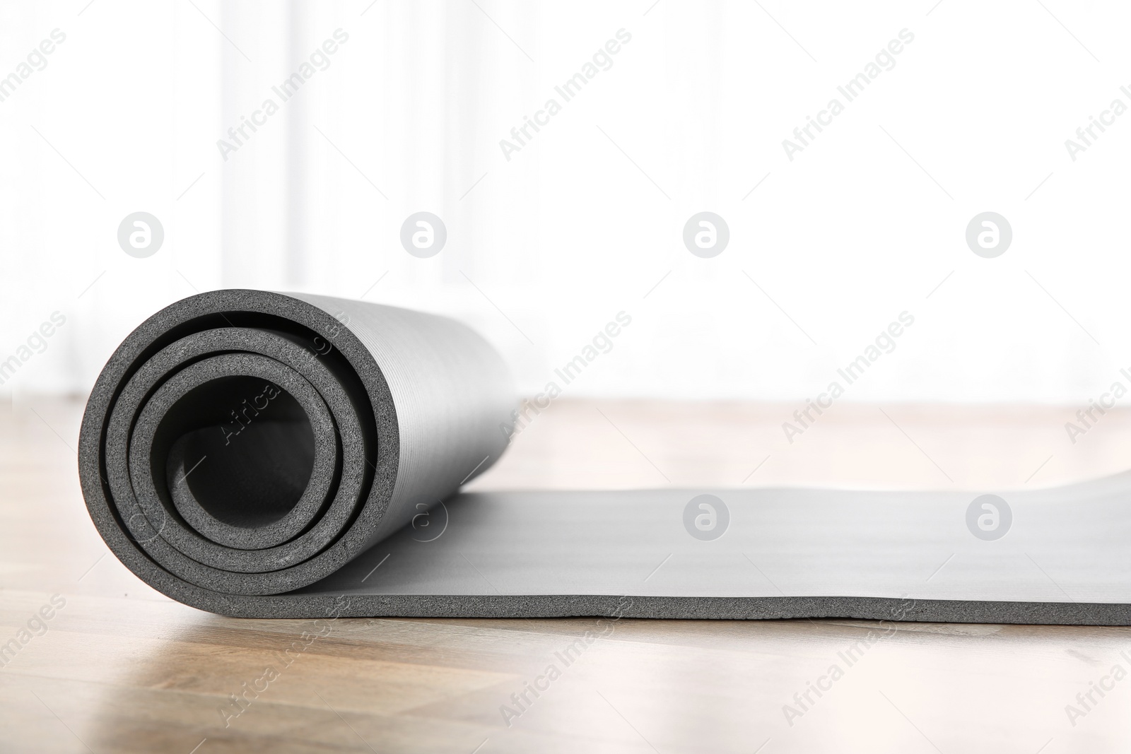 Photo of Rolled grey yoga mat on floor indoors