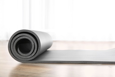 Photo of Rolled grey yoga mat on floor indoors