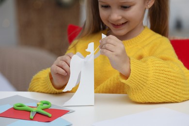 Cute little girl with paper angel for Saint Nicholas day at home, focus on hands