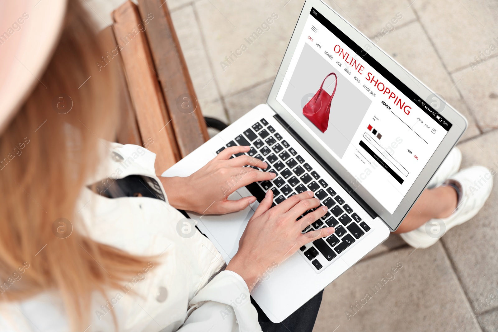 Image of Woman shopping online using laptop on bench outdoors, closeup