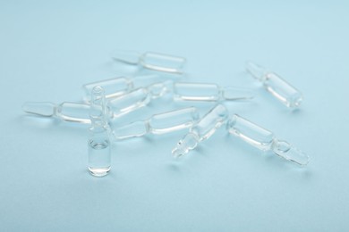 Glass ampoules with liquid on light blue background