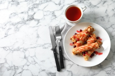 Photo of Thin pancakes with berries and syrup on plate, top view