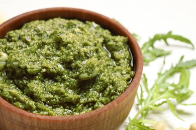 Bowl of tasty arugula pesto on table, closeup