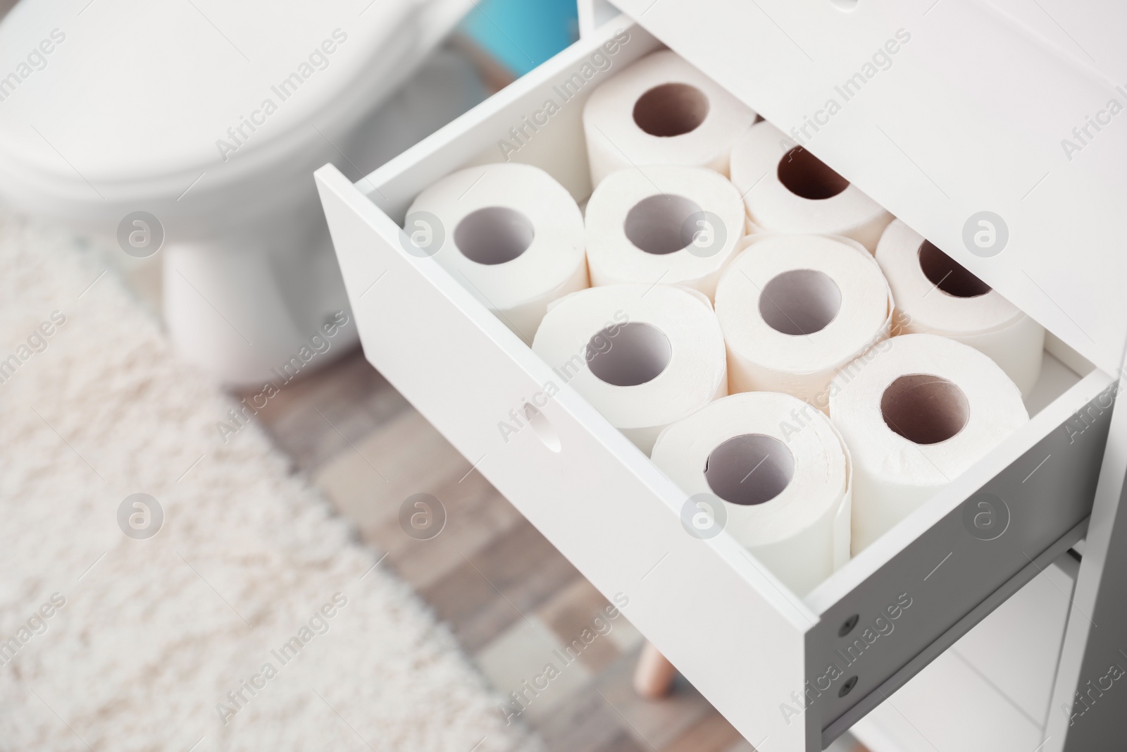 Photo of Open cabinet drawer with toilet paper rolls in bathroom