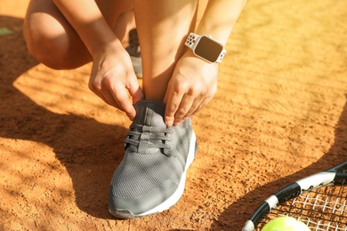 Woman wearing modern smart watch during training on tennis court, closeup