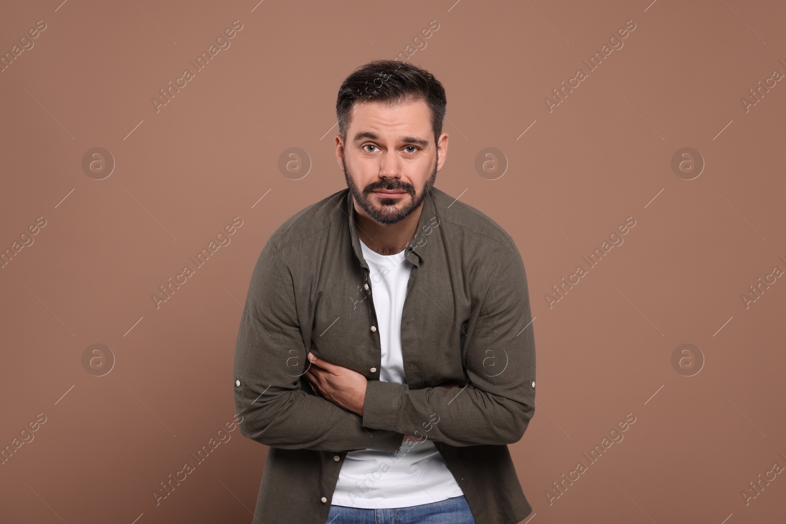 Photo of Man suffering from stomach pain on light brown background