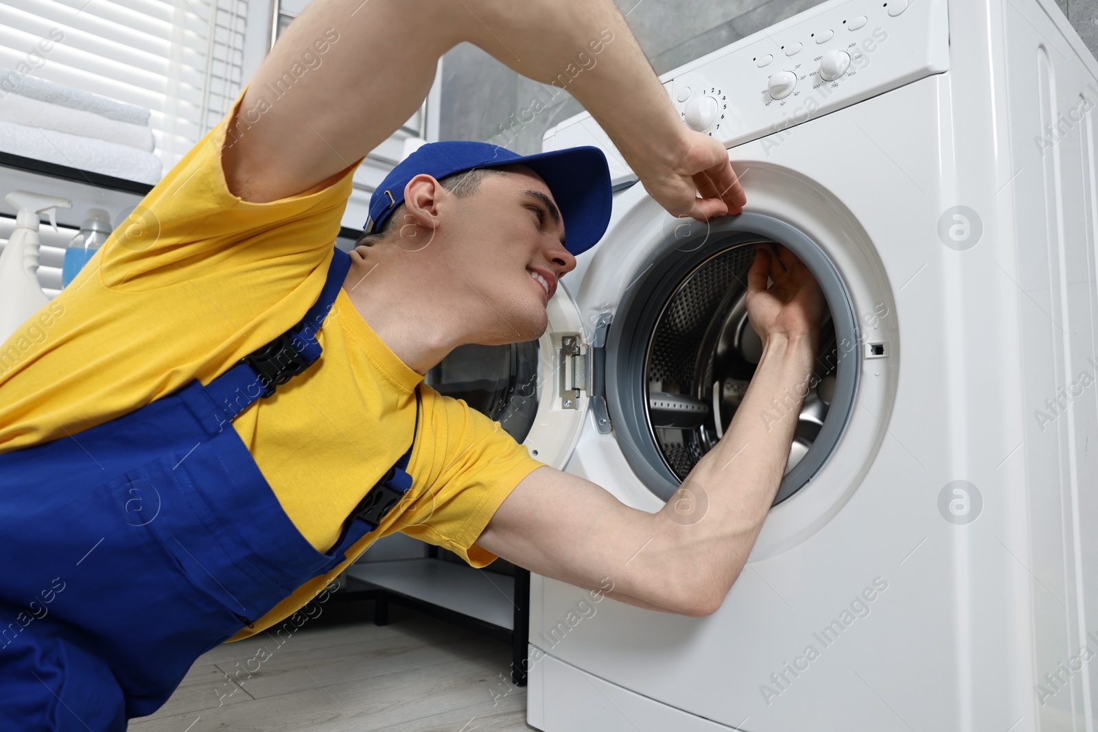 Photo of Smiling plumber checking door gasket of washing machine