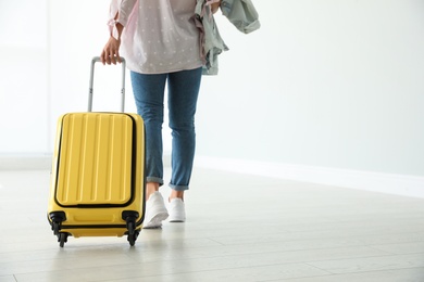 Photo of Woman with yellow travel suitcase in airport. Space for text