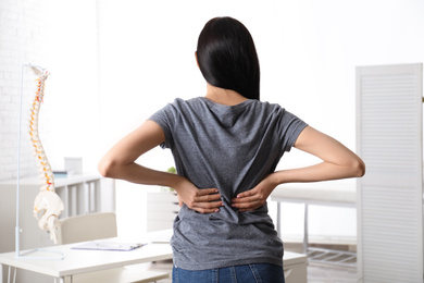 Woman suffering from lower back pain at clinic. Visiting orthopedist