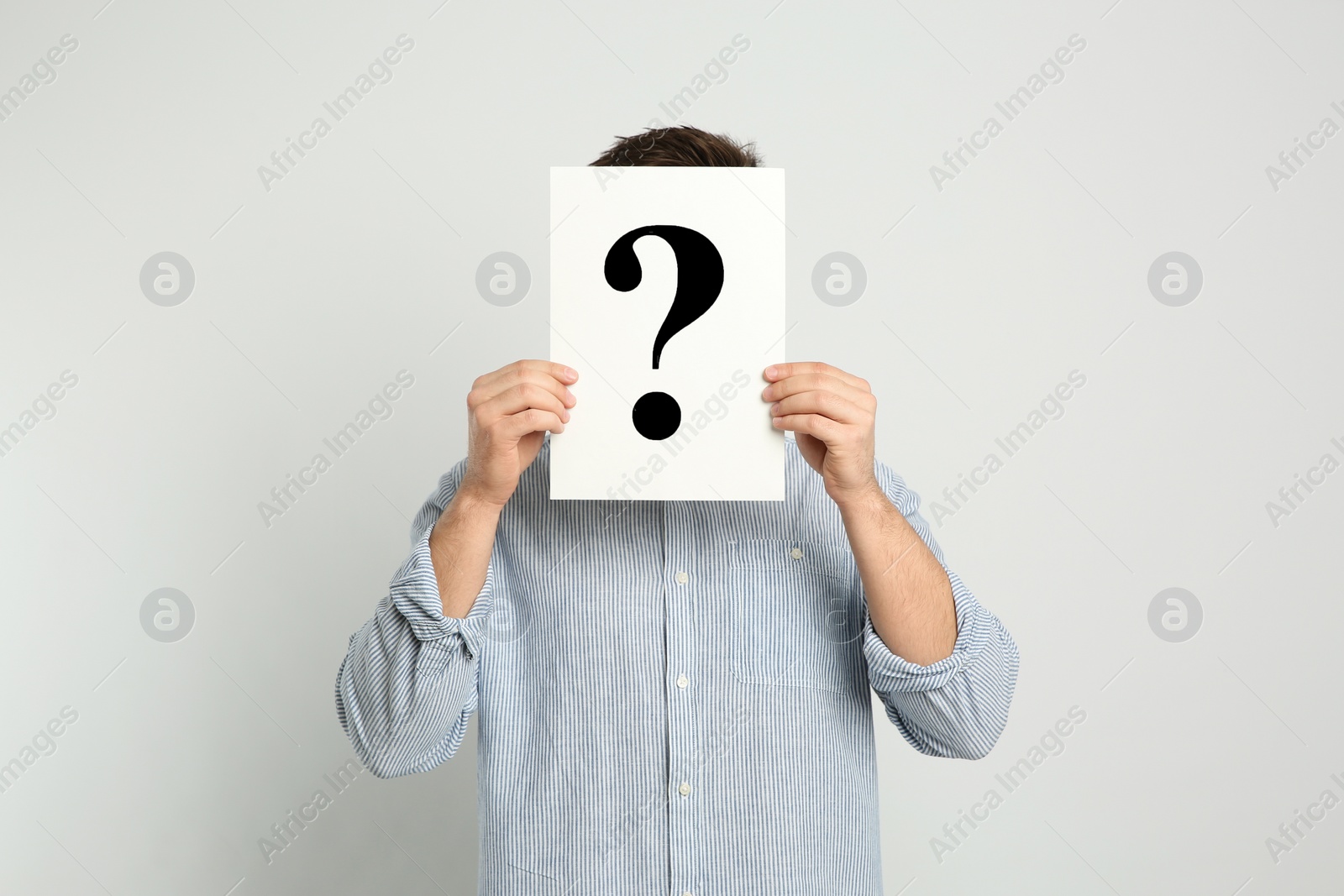 Photo of Man holding question mark sign on light background