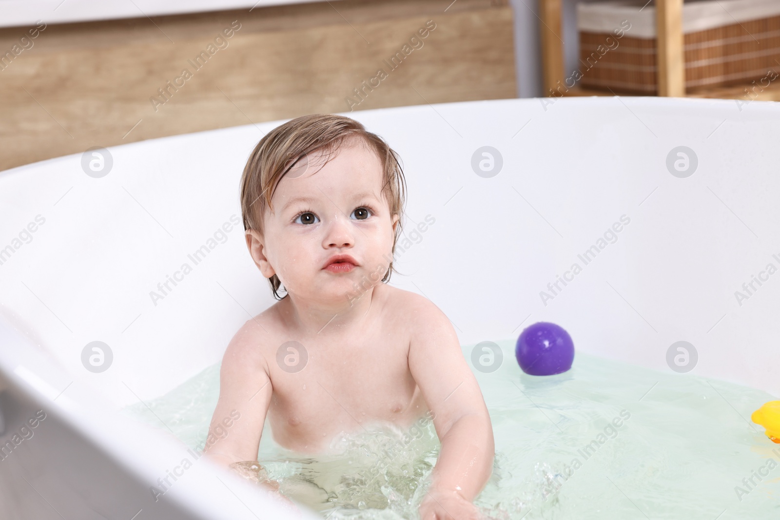 Photo of Cute little child bathing in tub at home