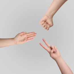 Image of People playing rock, paper and scissors on grey background, top view