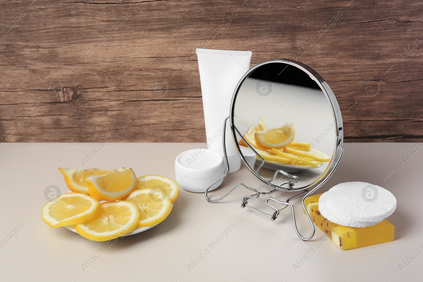 Photo of Lemon face wash. Fresh citrus fruits, personal care products and mirror on beige table