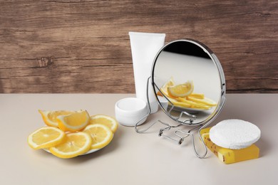 Photo of Lemon face wash. Fresh citrus fruits, personal care products and mirror on beige table