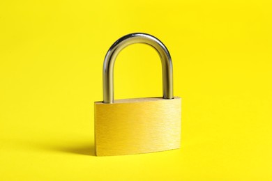 Photo of One locked steel padlock on yellow background