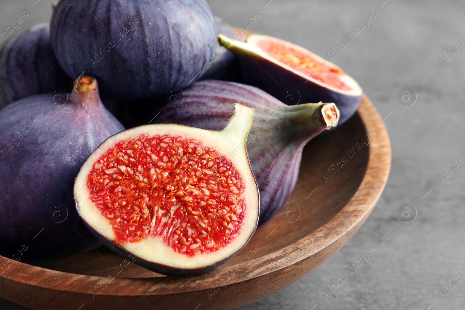 Photo of Bowl with fresh ripe figs on gray background. Tropical fruit