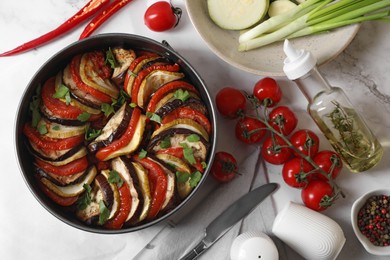 Photo of Delicious ratatouille, ingredients and knife on white table, flat lay