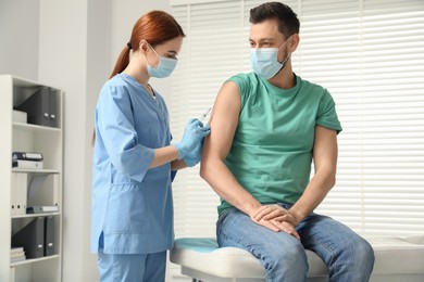 Doctor giving hepatitis vaccine to patient in clinic