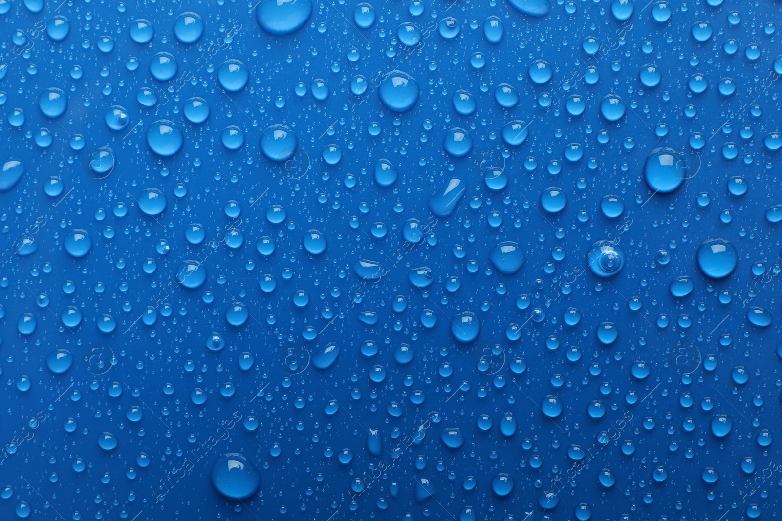 Photo of Water drops on blue background, top view