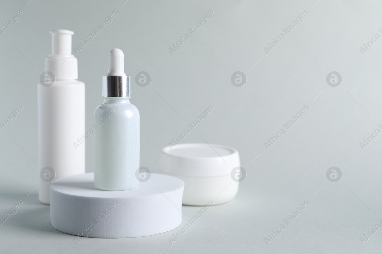 Photo of Bottles with cosmetic serums on light grey background, space for text