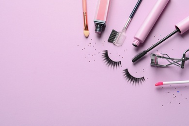 Photo of Flat lay composition with false eyelashes and other makeup products on pink background, space for text