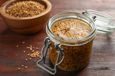 Whole grain mustard in jar on wooden table, closeup