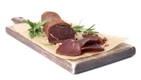 Photo of Delicious dry-cured beef basturma with rosemary and peppercorns on white background