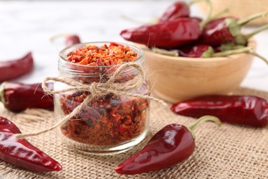 Photo of Chili pepper flakes and pods on table, closeup