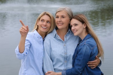 Photo of Happy mature mother and her daughters near pond