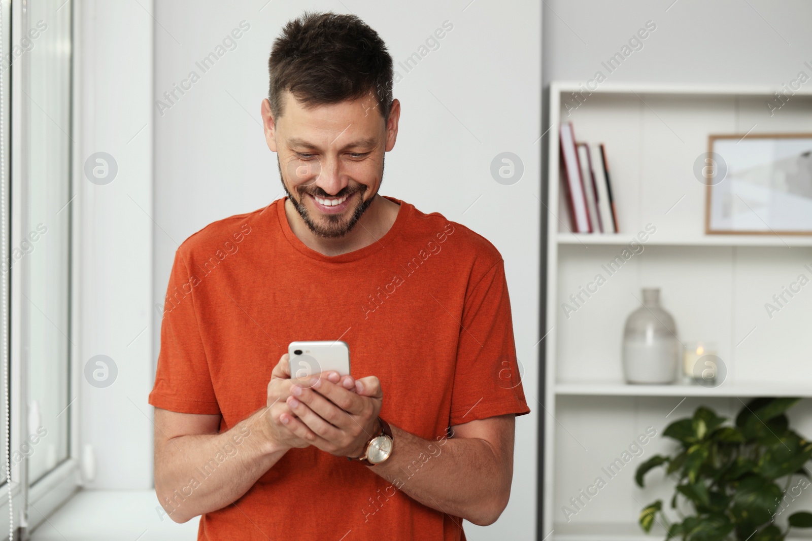 Photo of Happy handsome man using smartphone at home