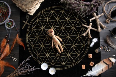 Photo of Voodoo doll with pins surrounded by ceremonial items on table, flat lay