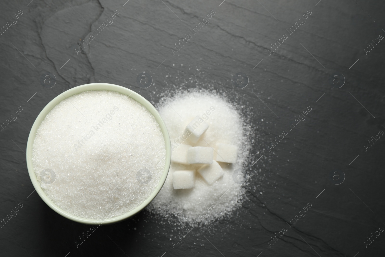 Photo of Flat lay composition with granulated sugar on dark table