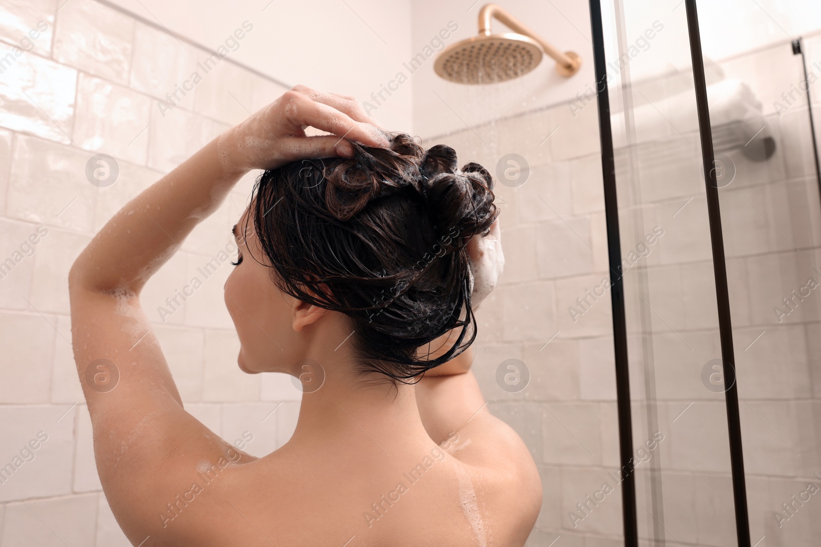 Photo of Woman washing hair while taking shower at home, back view