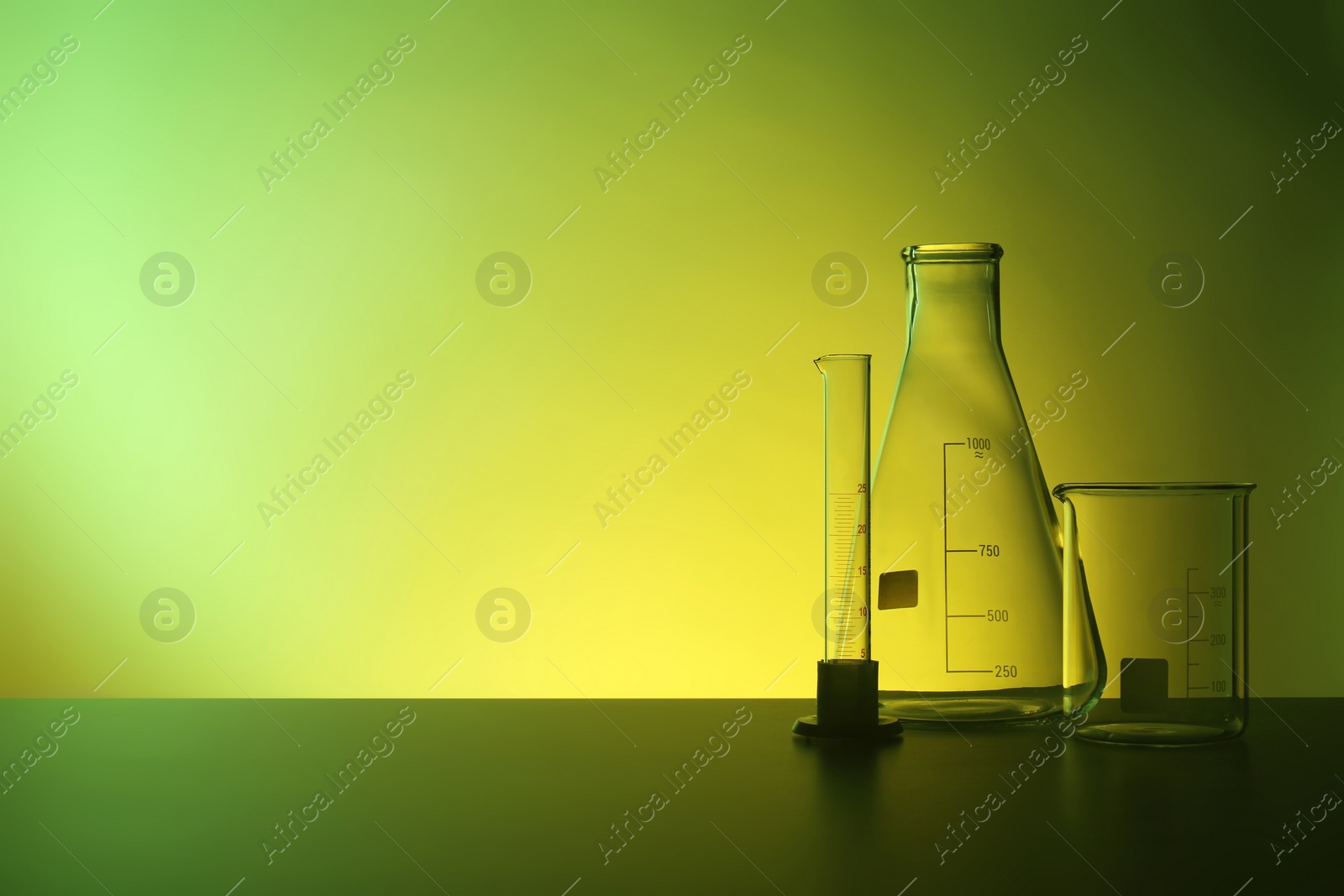 Photo of Empty chemistry laboratory glassware on table against color background