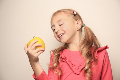 Cute little girl with apple on light background