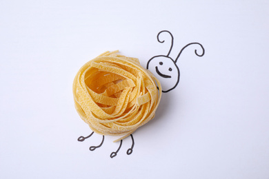 Photo of Funny bug made with tagliatelle pasta on white background, top view