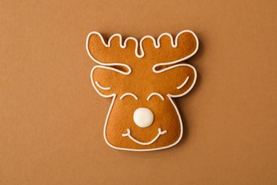 Photo of Christmas deer shaped gingerbread cookie on brown background, top view