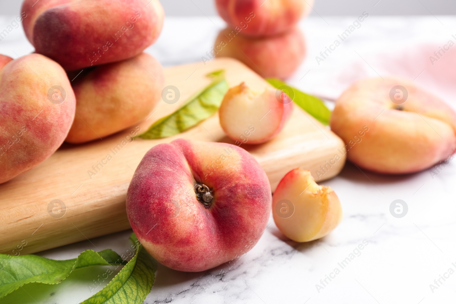 Photo of Fresh ripe donut peaches on white marble table, closeup