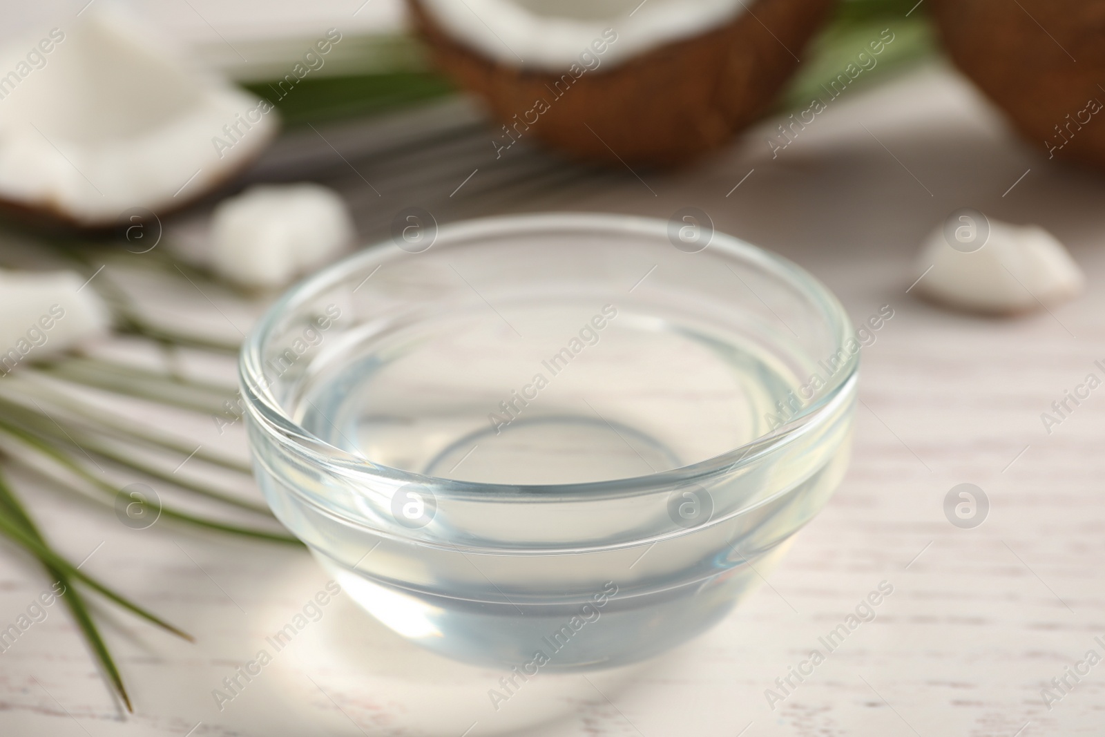 Photo of Coconut oil on white wooden table, closeup