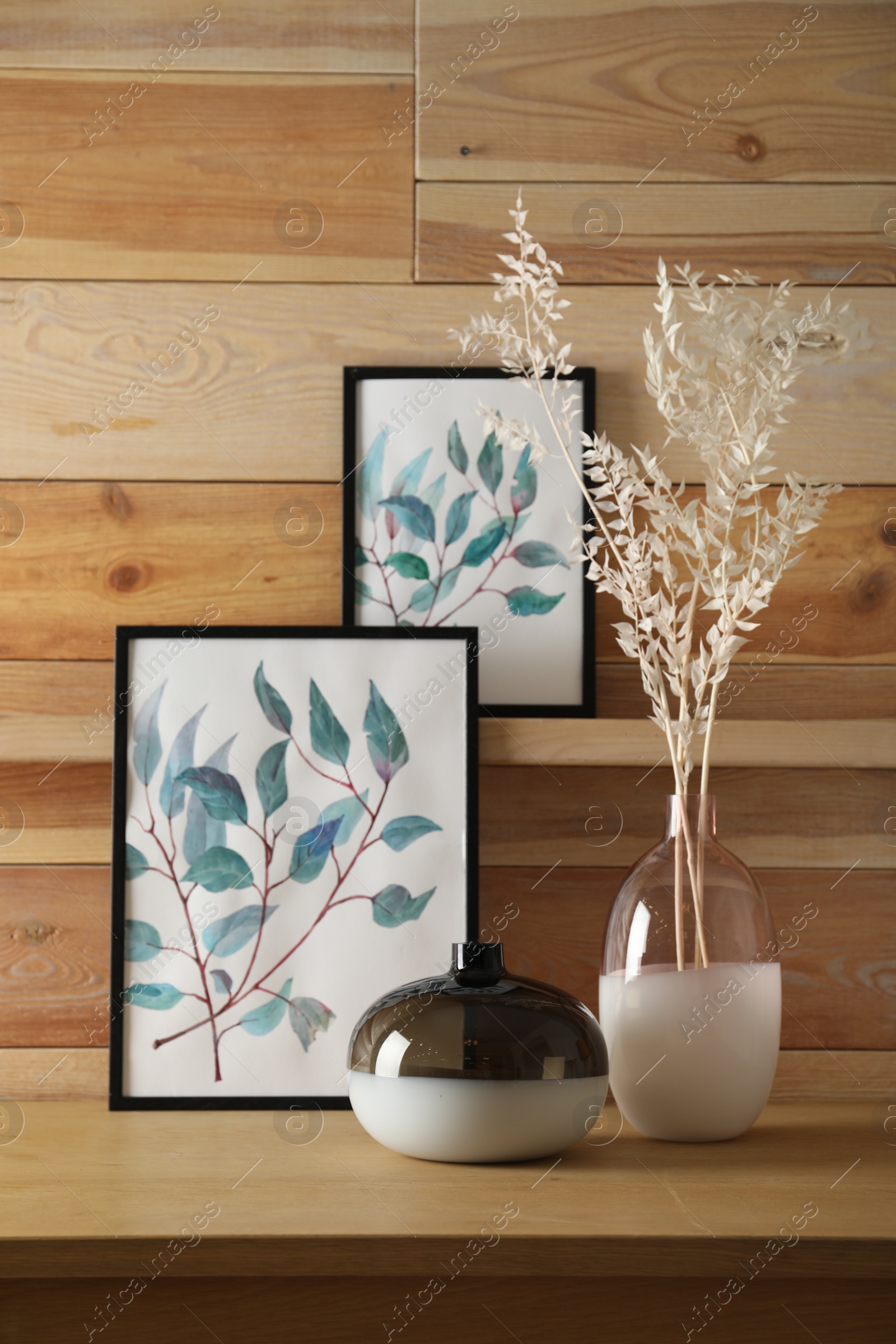 Photo of Decorative vases and pictures on wooden table