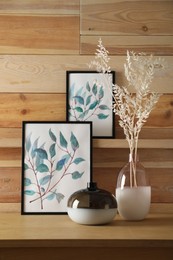 Photo of Decorative vases and pictures on wooden table